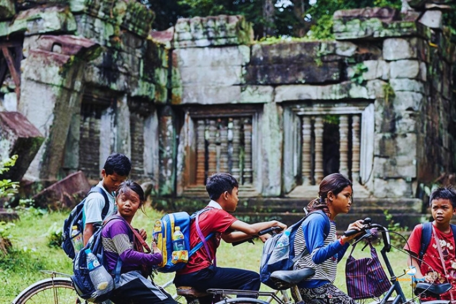 Cambodian children cycling near ancient temple ruins – Auasia Travel